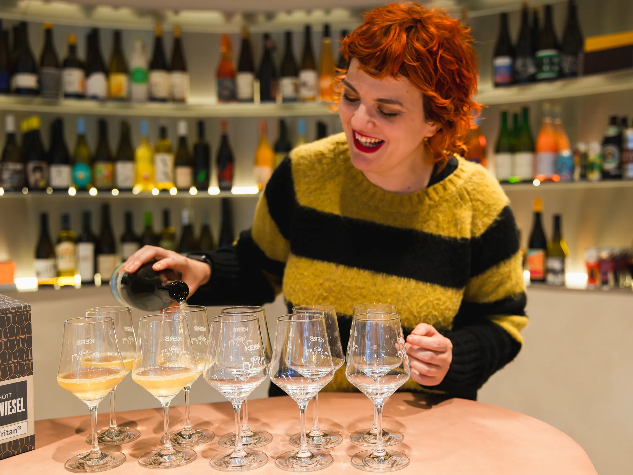 Photo of Kelly Bishop, smiling and pouring out glasses of wine for her guests on a Manchester Wine Tour
